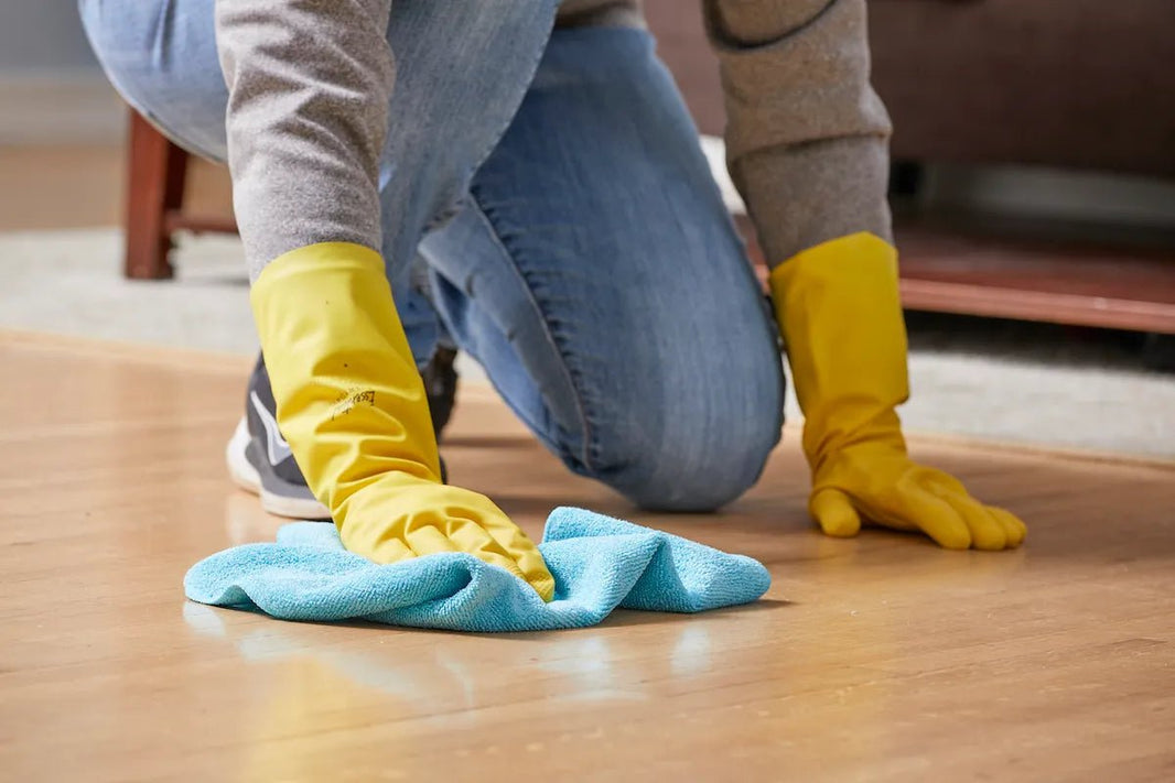 woman kneeling on hardwood, dry wiping the floor with a cloth