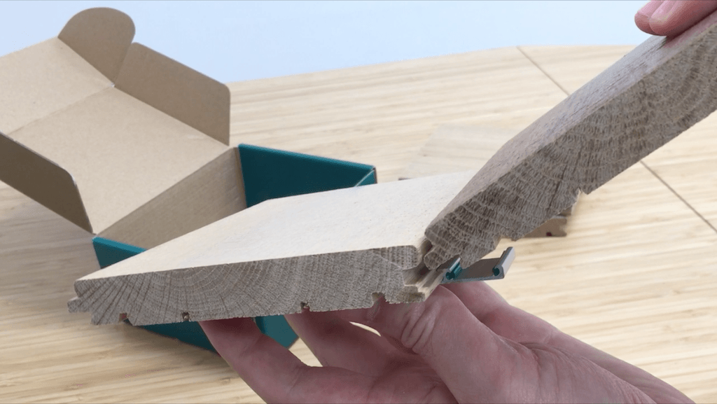 Close-up of an Easiklip floating hardwood flooring sample, showcasing its solid oak construction and pre-attached clip system for easy installation without nails or glue.